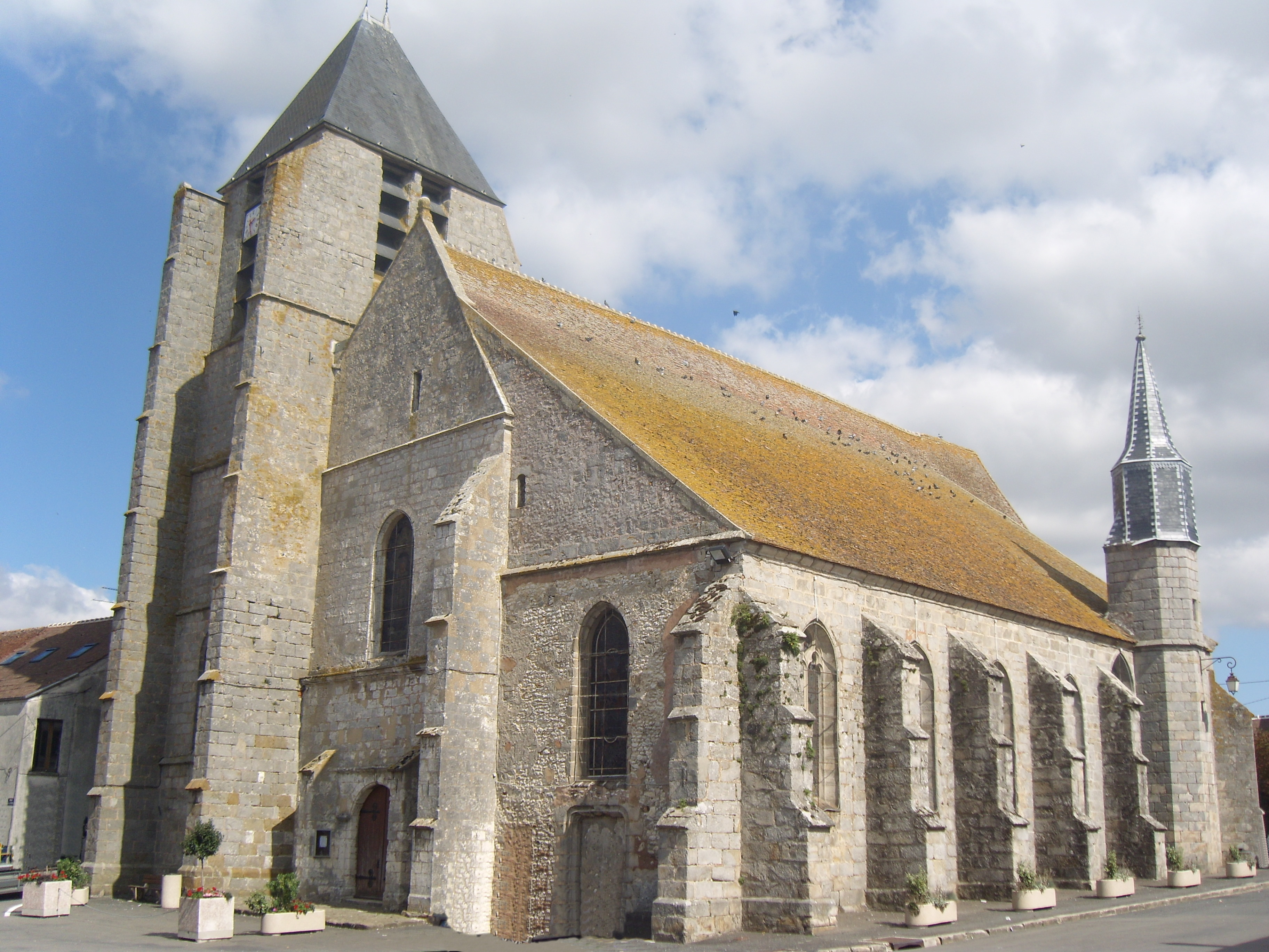 Vue extérieure de l'église St AubinLa construction primitive remonterait au XIe siècle, époque à laquelle l'église appartenait aux chapelains de la cathédrale de Reims. L’Eglise comporte trois nefs sans transept. L'église primitive était dans le collatéral sud. En 1392, la porte d’entrée de ce collatéral sud fut bouchée et le collatéral nord fut prolongé pour l’installation d’une chapelle. Le bas-côté a été séparé du chœur par une balustrade et le clocher qui le surmontait a été déplacé. On distingue encore l’ancien portail roman et les bases romanes des piliers circulaires édifiés lorsqu'au XVe siècle les nefs ont été refaites. Le choeur, voûté en pierre, ne fut retouché que lors de la restauration générale de 1723. On accomoda alors l’ancien style du XV au goût de la Renaissance du XVIe.